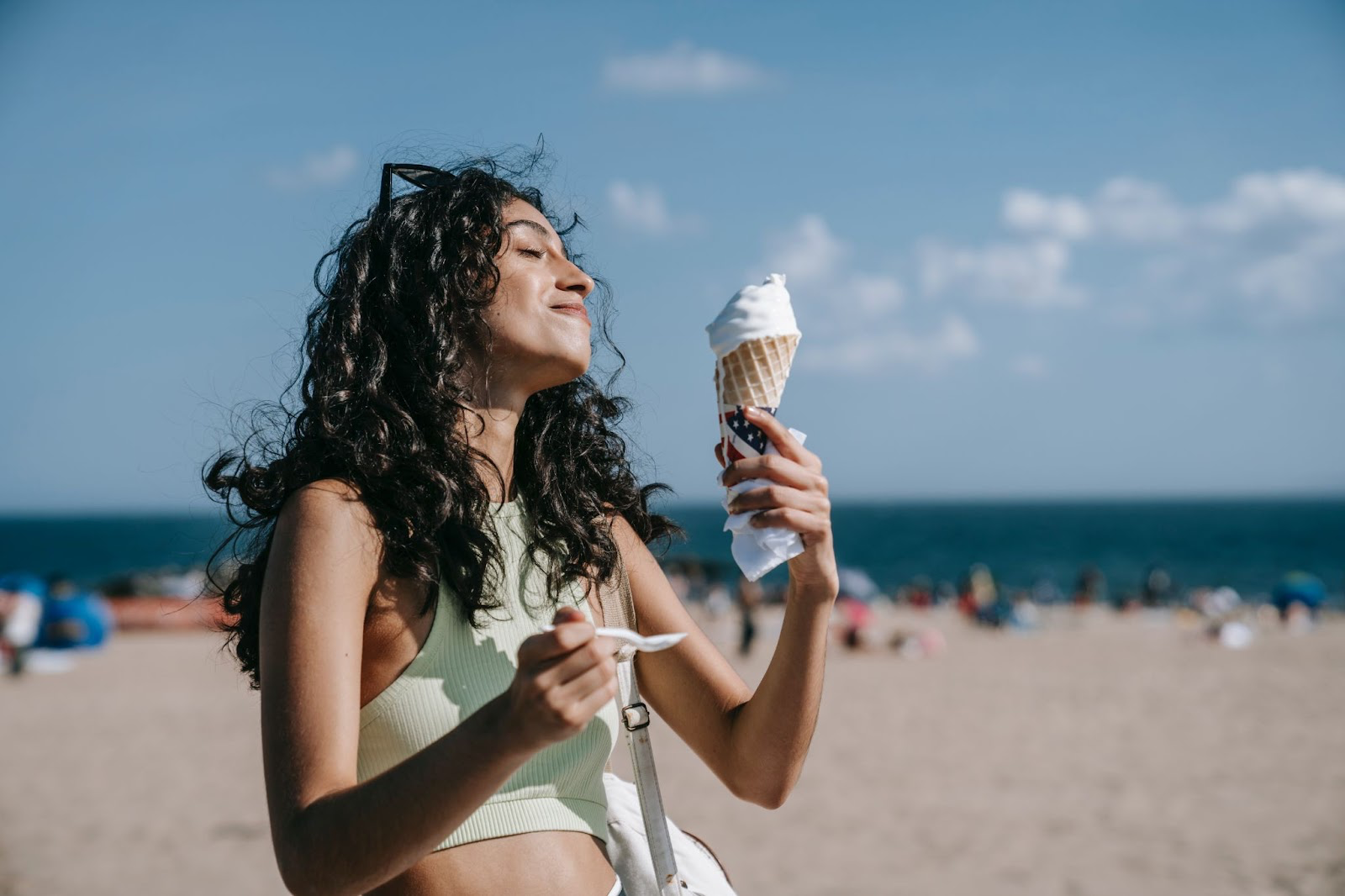 Curly woman eating ice cream at the beach